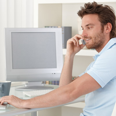 A photo of a man on the phone and using his laptop as a metaphor for communication of an Oakford Group stakeholder