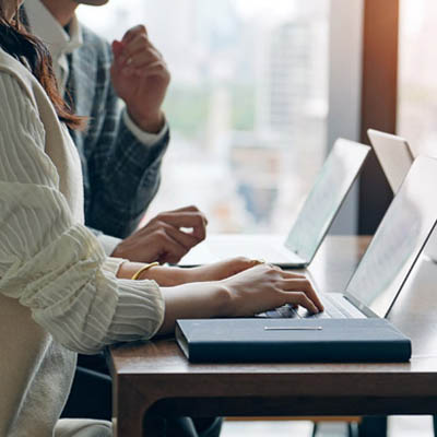 Professionals working on laptops by a window overlooking a city, reflecting Oakford Group's data-led residential operations in South East England