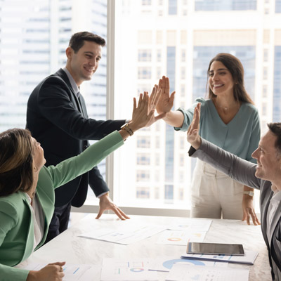 Business team celebrating with a high five, reflecting the teamwork and shared mission of Oakford Group